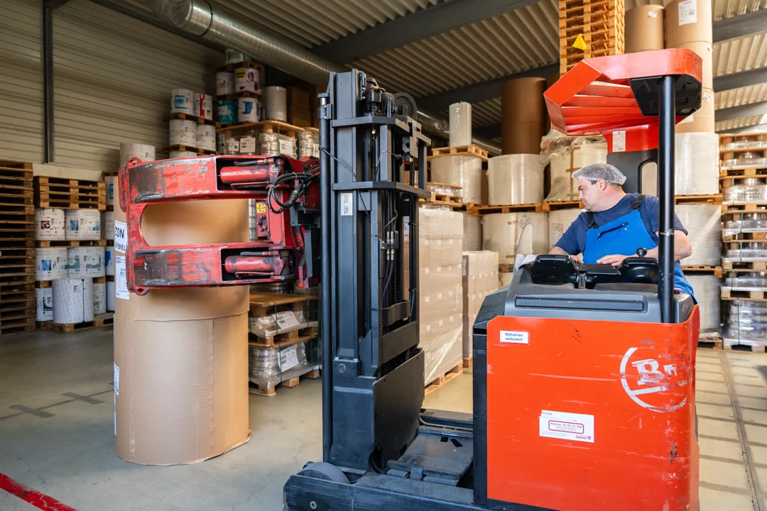 Mitarbeiter mit dem Kommissionierstapler im Papierlager