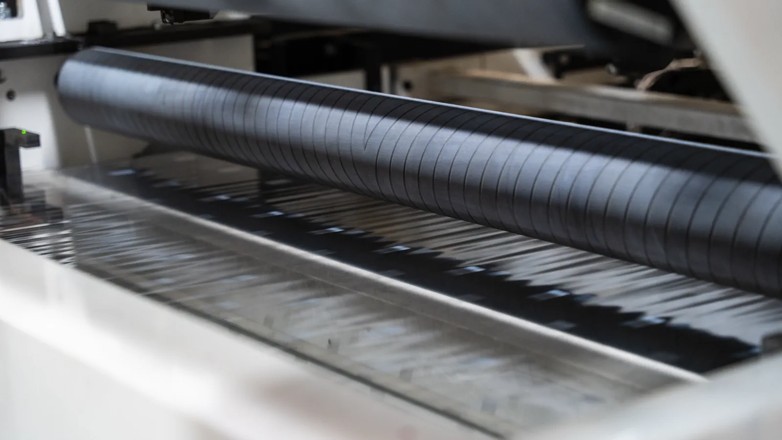 Nahaufnahme einer Walze mit laufender Materialbahn in einer Flexopack-Druckmaschine